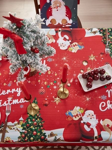Detail of red Christmas tablecloth with Santa Claus and festive tree patterns