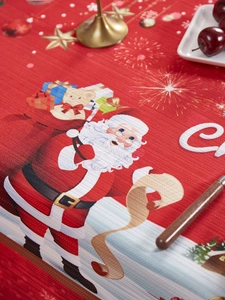 Detail of red Christmas tablecloth featuring Santa and Teddy Bear with festive decor