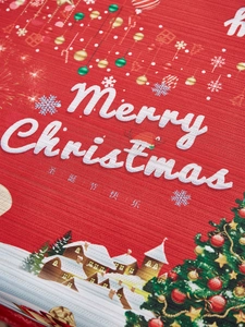 Close-up of red Christmas tablecloth featuring Merry Christmas text and festive village pattern