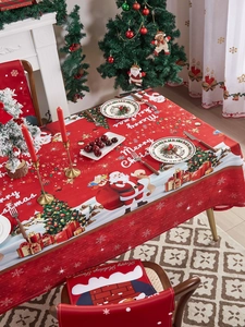 Detailed view of red Christmas tablecloth and matching chair covers with Santa Claus motifs