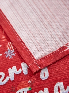 Detailed close-up showing the red Christmas tablecloth fabric texture and edge stitching