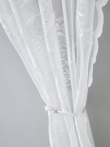 Close-up of white French lace door curtain with floral embroidery and wavy scalloped edges