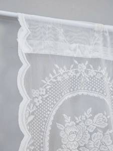 Detail of white French lace curtain with floral net pattern and scalloped edges