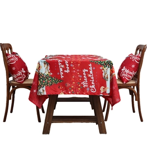 Red Christmas tablecloth with Merry Christmas print and festive tree patterns on a wooden table