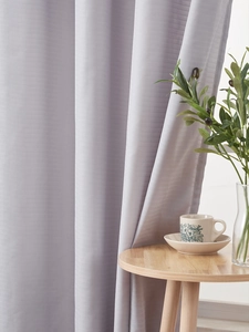 Detail of lavender sheer curtain showing luxury textured fabric in a cozy living room