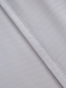 Close-up of light gray sheer curtain with detailed twill weave and precision stitching