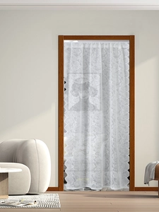Detail of white vintage lace door curtain with floral patterns and wavy scalloped edges