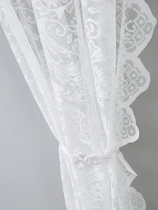 Detailed view of white French lace curtain with delicate floral hollow patterns and wavy edges