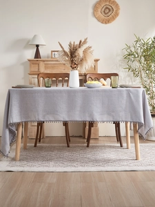 Close-up of light gray textured table runner with elegant pom-pom fringe details