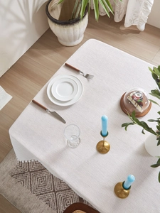 Detail of grey textured tablecloth with white pom-pom trim in a Nordic dining setting