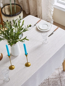 Detailed texture of beige linen tablecloth with white mini pom-pom fringe and home decor