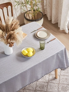 Macro shot of grey linen tablecloth with elegant pom-pom trim and detailed fabric texture