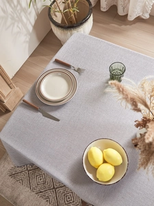 Close-up of thick light gray faux linen tablecloth texture with soft lighting on a table