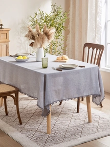 Detail of light purple linen texture tablecloth with decorative pom-pom trim edge