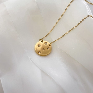 Vue détaillée du pendentif rond plaqué or 18K avec gravures en étoile et petits diamants