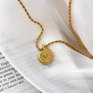 Détail de la chaîne torsadée en acier plaqué or 18K avec médaillon à texture rayonnante