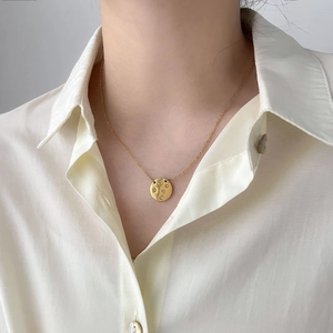 Gros plan du collier pendentif rond gravé d'étoiles avec pierres blanches sur un mannequin