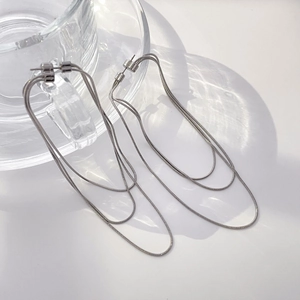 Macro detail of triple-layer silver snake chain fringe earrings on glass display