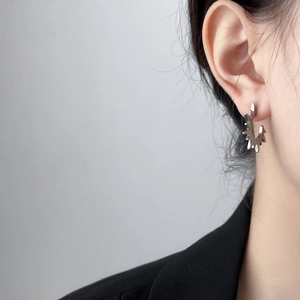 Silver punk style gear earrings shown on a model wearing a black suit jacket