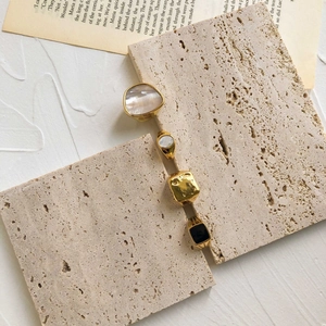 Détails de quatre bagues vintage dorées avec incrustation de nacre et émail noir sur travertin