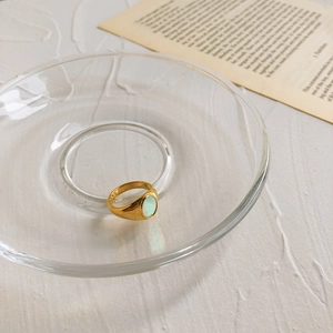 Vue détaillée d'une bague dorée en nacre ovale posée sur du papier vintage