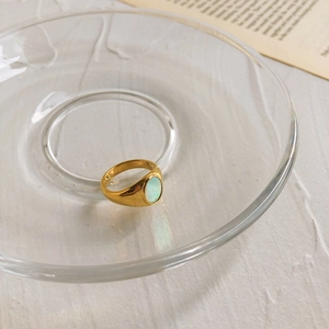 Vue macro détaillée d'une bague dorée avec pierre de lune ovale sur support blanc