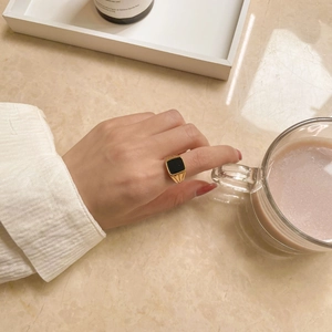 Gros plan d'une bague carrée vintage en plaqué or avec incrustation d'onyx noir