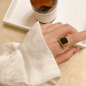 Détail d'une bague dorée vintage avec émail noir et anneau texturé gravé