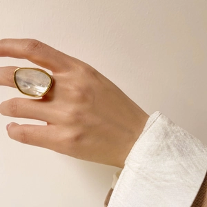 Bague épaisse en or minimaliste avec incrustation de nacre ovale portée par un modèle
