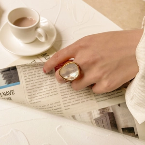 Gros plan d'une bague dorée massive ornée d'une grande nacre aux reflets irisés
