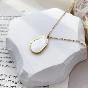 Gros plan du pendentif en nacre ovale sur un collier délicat en titane plaqué or 18 carats