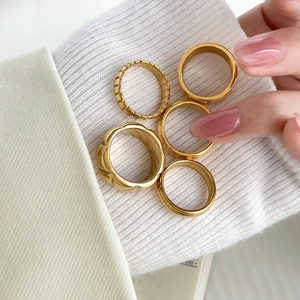 Detail of 18K gold-plated multilayer ring set showing diverse textures on knit fabric