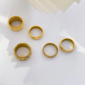 Set of five gold stacked rings with varied textures like ribbing and diamond patterns
