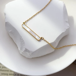 Gros plan d'un collier doré avec pendentif rectangulaire serti de nacre blanche naturelle