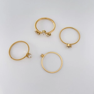 Detail of four gold rings set featuring twisted bands and clear zircon stone accents