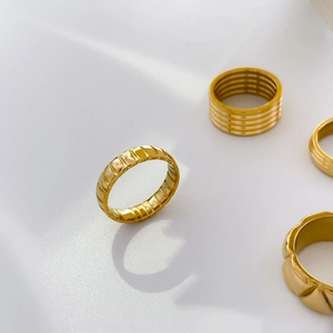 Detail of four 18K gold plated stackable rings with textured ridges and layered bands