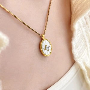 Détail d'un collier ovale en nacre plaqué or 18K avec zircon sur un mannequin