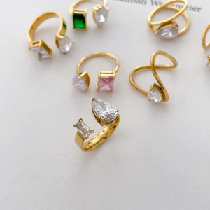Détail de bagues plaquées or 18 carats avec zircons cubiques poire et carrés, émeraude et rose