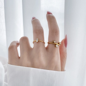 Detailed view of layered 18K gold plated titanium rings with marquise and round zircons