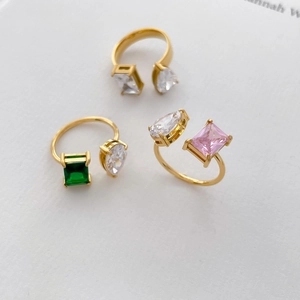 Détail de bagues double couche plaquées or 18 carats avec pierres émeraude et rose