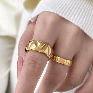 Detail of layered gold titanium rings with geometric triangle texture on female hand