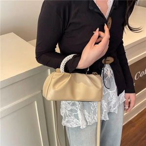 Sac nuage froncé beige avec poignée en perles et bandoulière en cuir porté par mannequin
