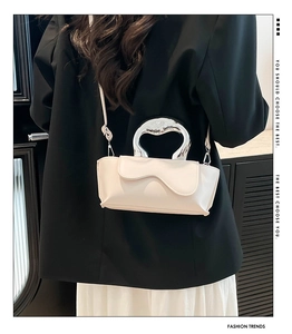 Detail view of cream PU crossbody bag with silver sculptural handle on a model