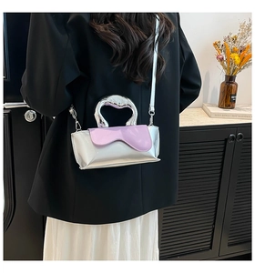 Detail of silver metallic crossbody bag with purple flap and unique metal handle