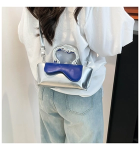 Detail of silver metallic handbag with blue wave flap and sculptural metal handle