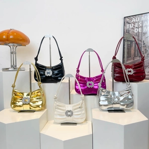 Elegant pleated hobo bag in six metallic colors with a rhinestone buckle on white stairs