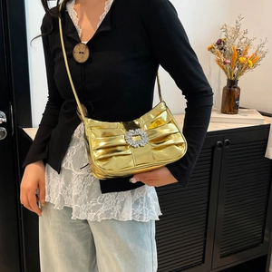 Chic gold pleated hobo bag with rhinestone buckle shown on model in modern room