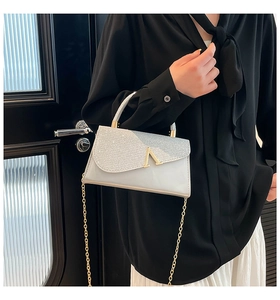 Detail of silver glitter crossbody bag with V-shaped buckle and gold chain strap