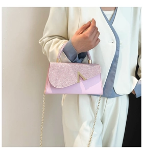 Detail of pink rhinestone handbag with gold V-metal clasp and circular handle worn by model