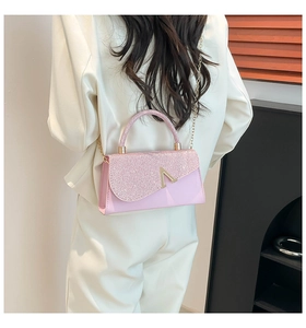 Close-up of pink glitter flap bag with golden V-buckle and metallic chain strap